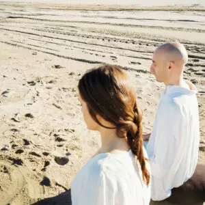Imagen desde un lado de Jordi Ibern y una alumna practicando meditación en la playa